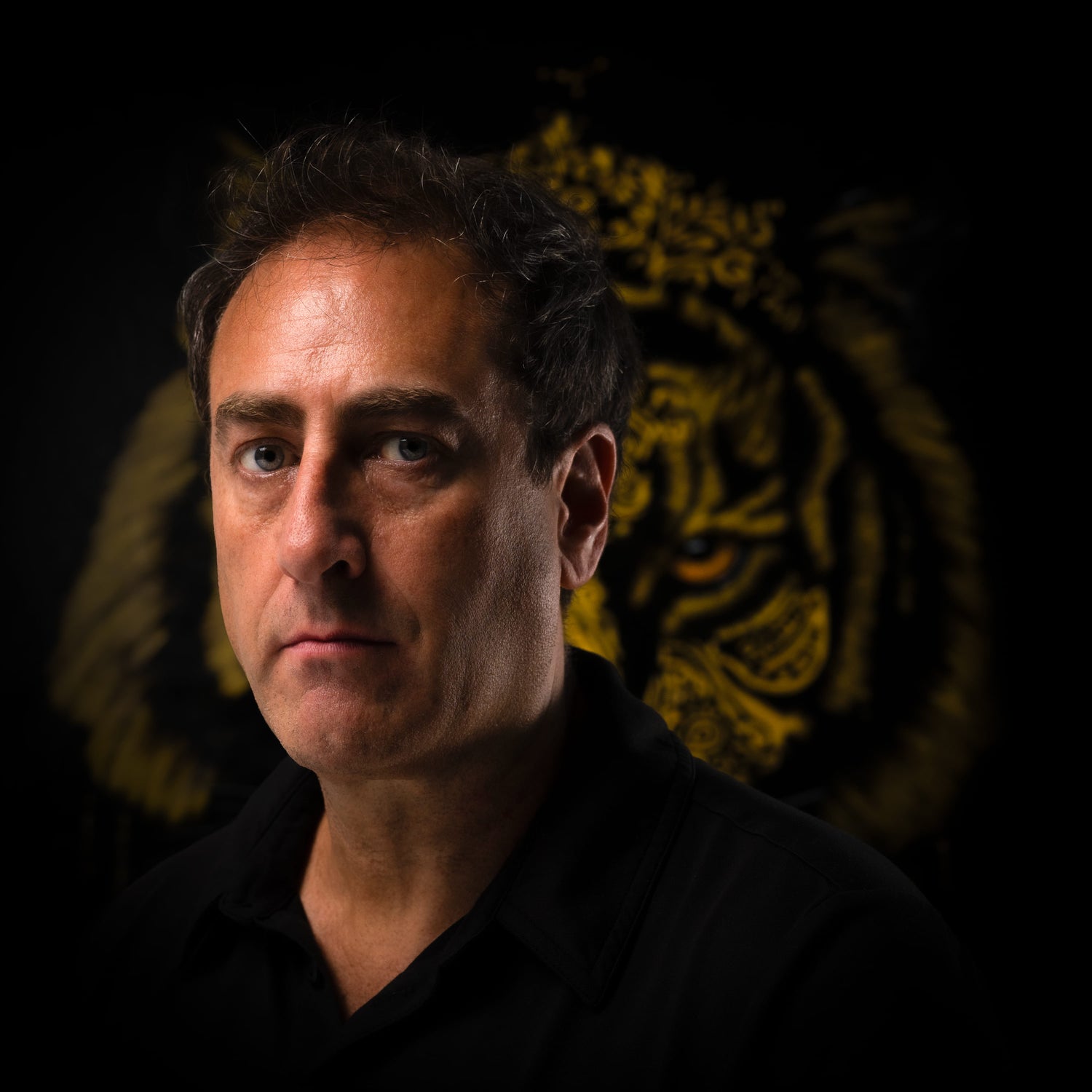 Man in a dark shirt with a lion emblem in the background