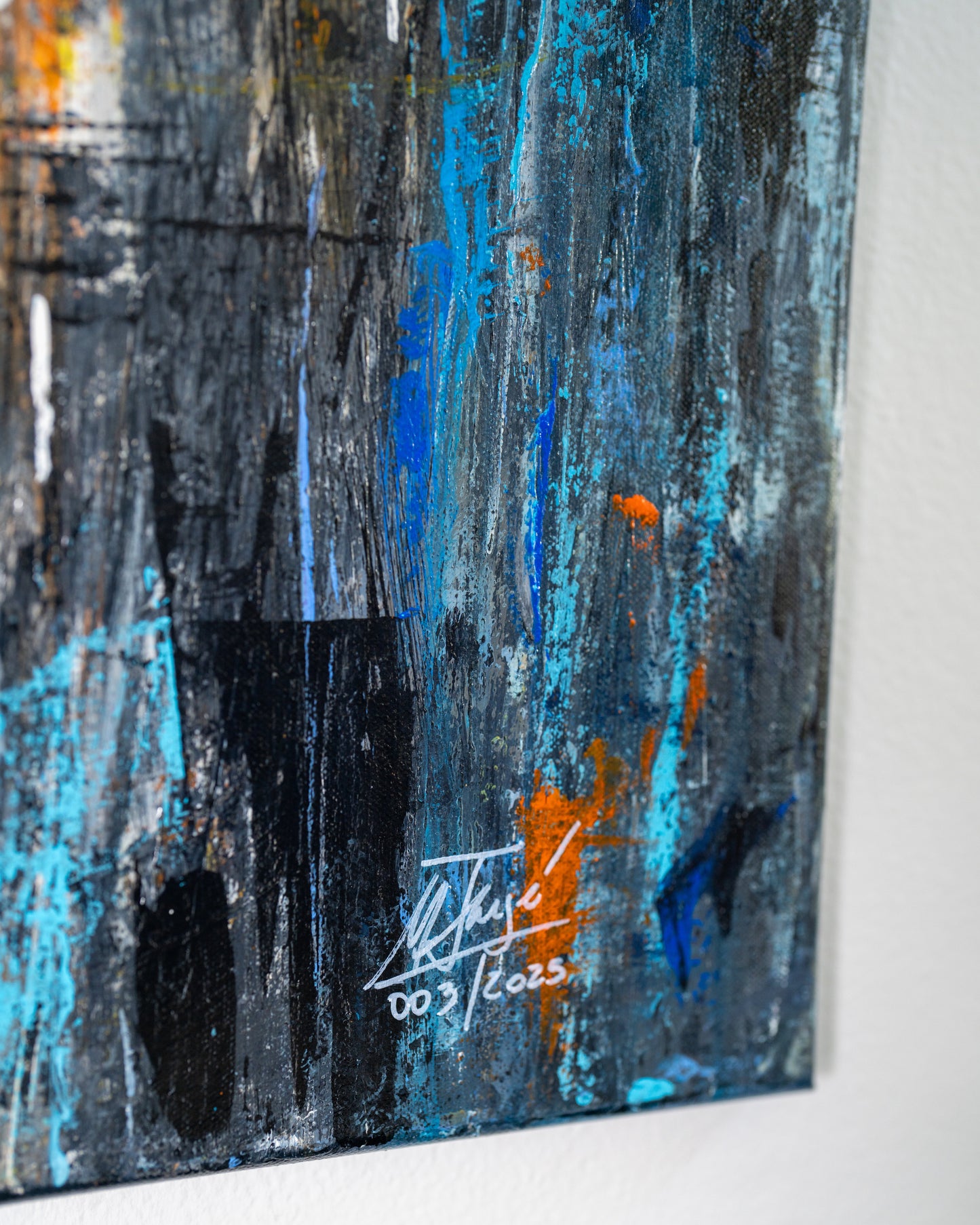 Abstract painting with blue and orange tones on a white wall.