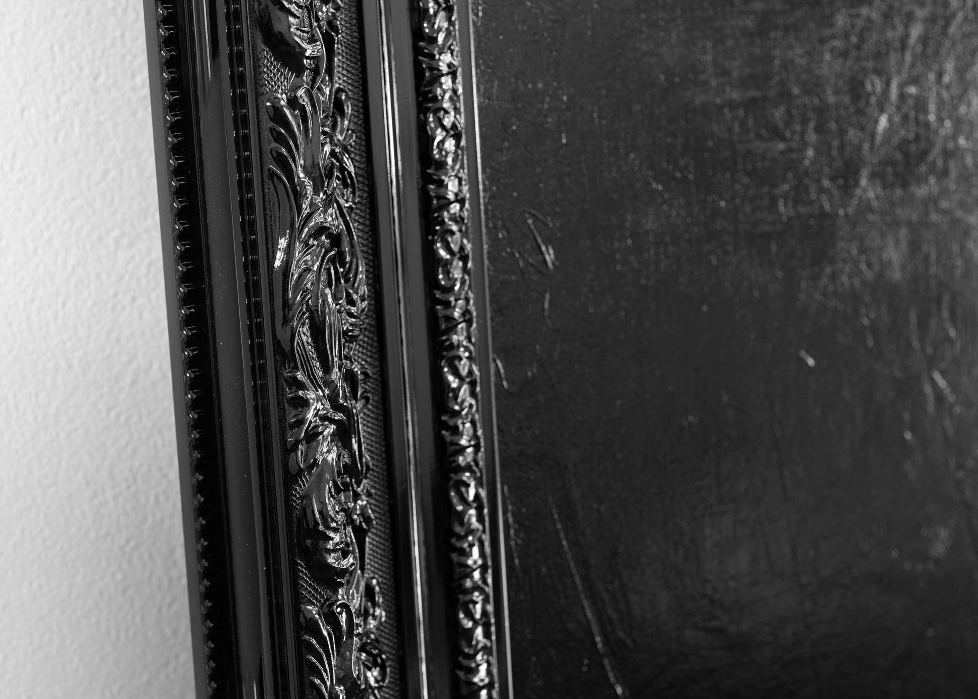Close-up of an ornate black picture frame on a white wall.