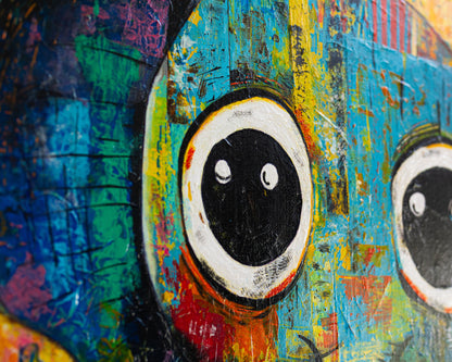 Close-up of a colorful abstract painting with prominent eyes.