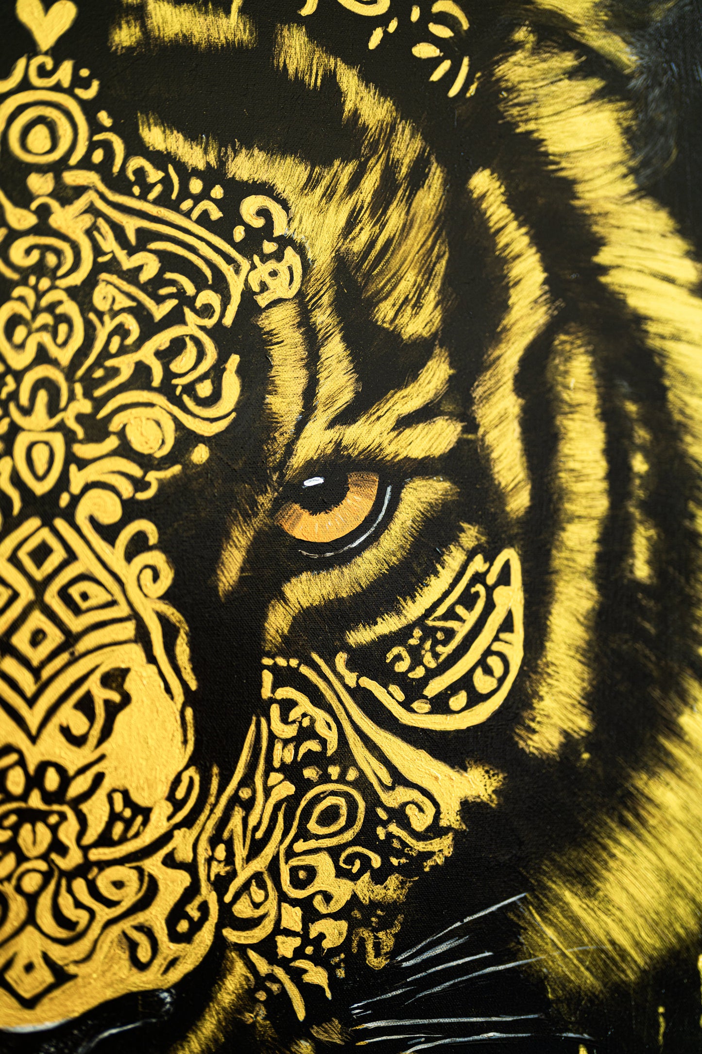 Close-up of a tiger's face with intricate yellow patterns on a black background